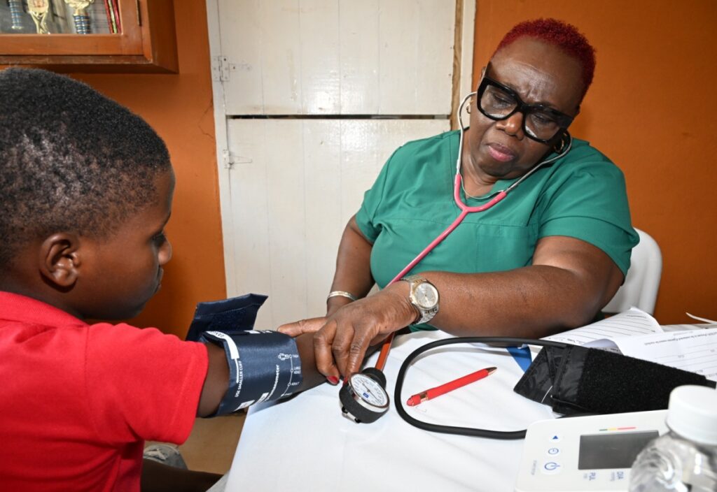 Medical assistant Aleita Fullerton checks vitals of young Davario Taylor at the Mission health fair 9/6/26 at Barbican Church in St Andrew Jamaica.